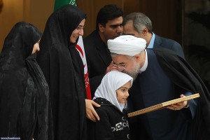 Iran's President Hassan Rouhani celebrates the completion of an interim deal on Iran's nuclear program on Nov. 24, 2013, by kissing the head of the daughter of an assassinated Iranian nuclear engineer. (Iranian government photo) 